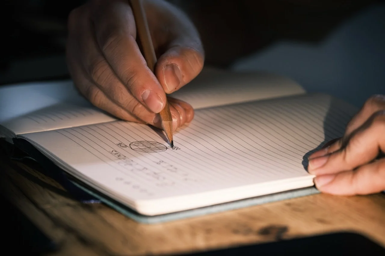 une main ecrivant sur un cahier avec des graphiques