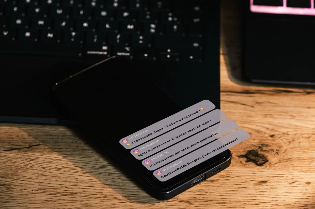 un téléphone posé sur un bureau avec des notifications de réseaux sociaux